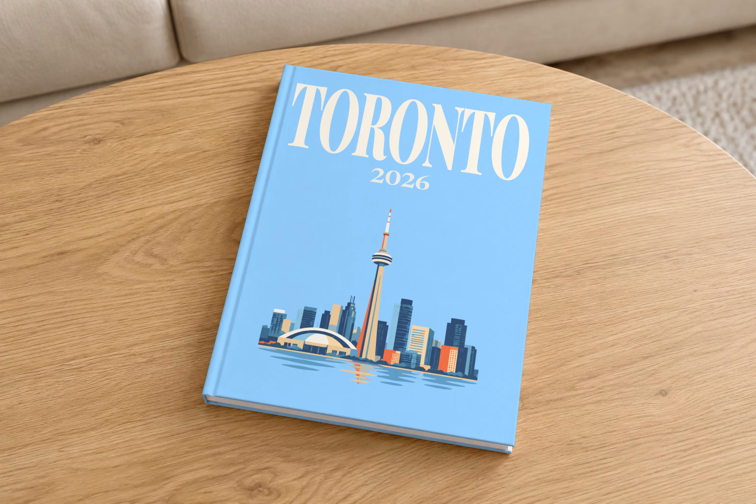 Canada hardcover photo book with the Toronto illustrated cover of the Toronto skyline and CN Tower on pale blue, on a round oak coffee table in a bright living room