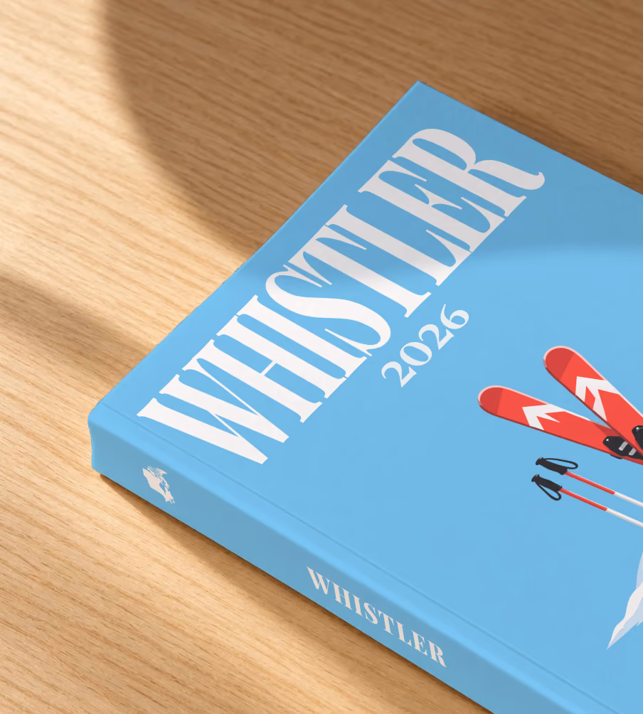 Canada softcover photo book with the Whistler illustrated cover of red skis and poles in snow on sky blue, lying on an oak desk in dappled afternoon sunlight