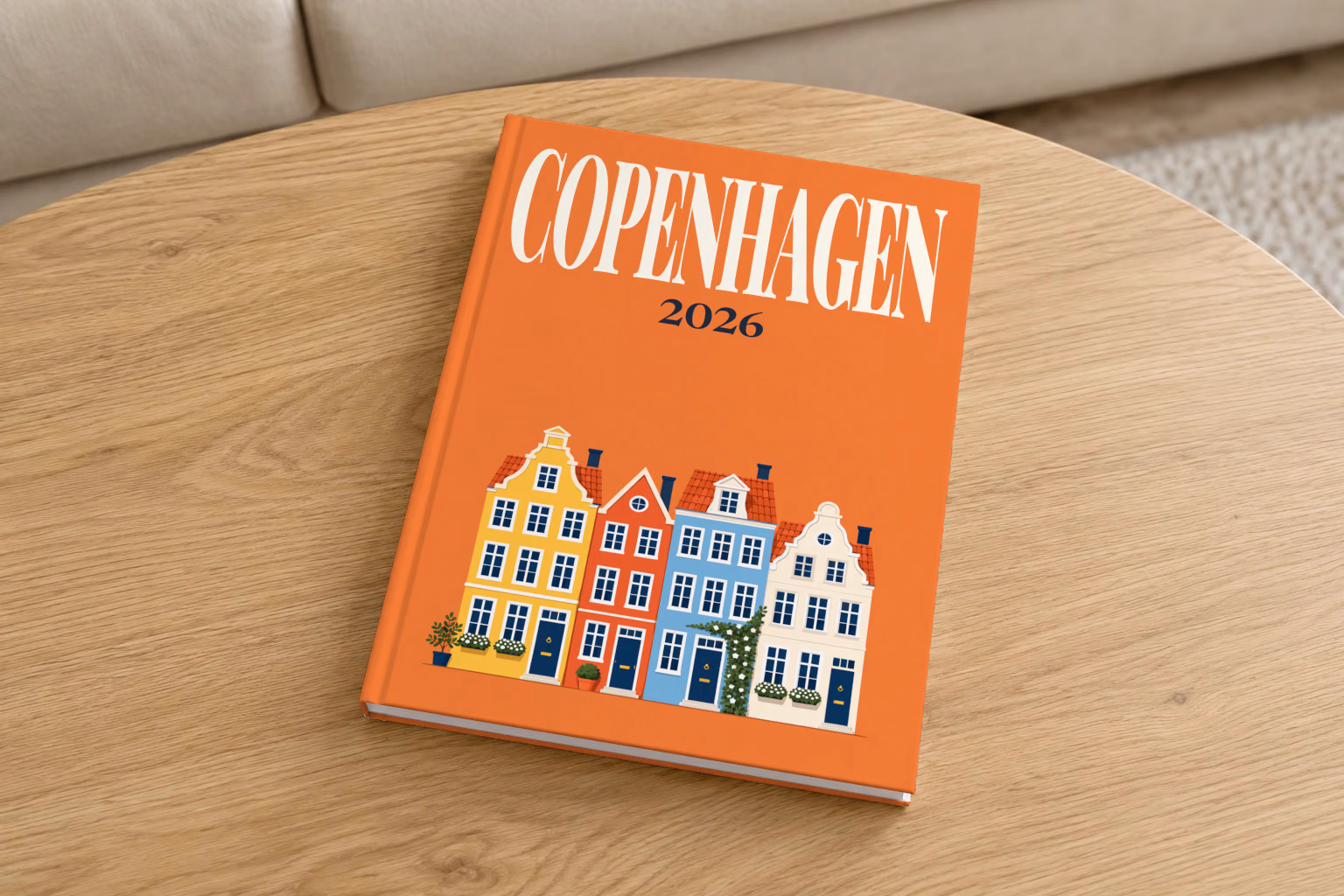 Denmark hardcover photo book with the Copenhagen illustrated cover of the colourful Nyhavn harbour houses on orange, on a round oak coffee table in a bright living room