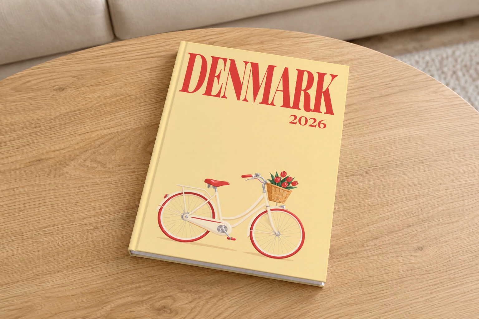Denmark hardcover photo book with the illustrated cover of a Danish bicycle with a basket of red tulips on pale yellow, on a round oak coffee table in a bright living room