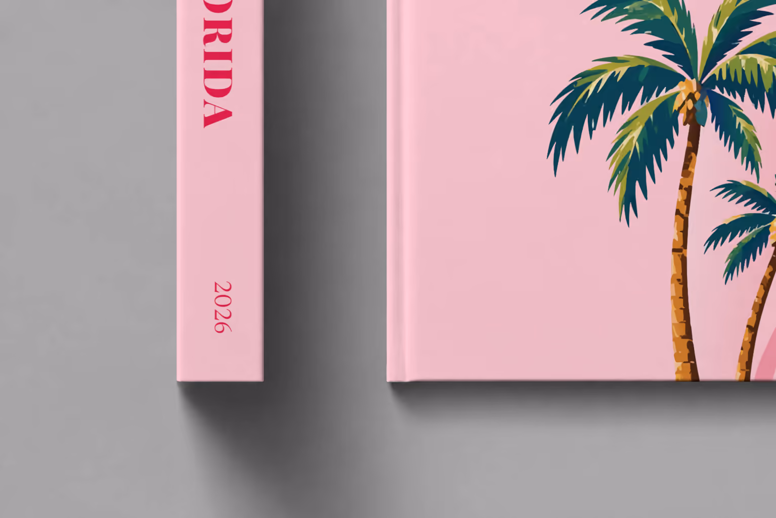 Florida hardcover photo book with the illustrated cover of Florida palm trees on pink, shown close up beside its spine on a pale grey studio surface