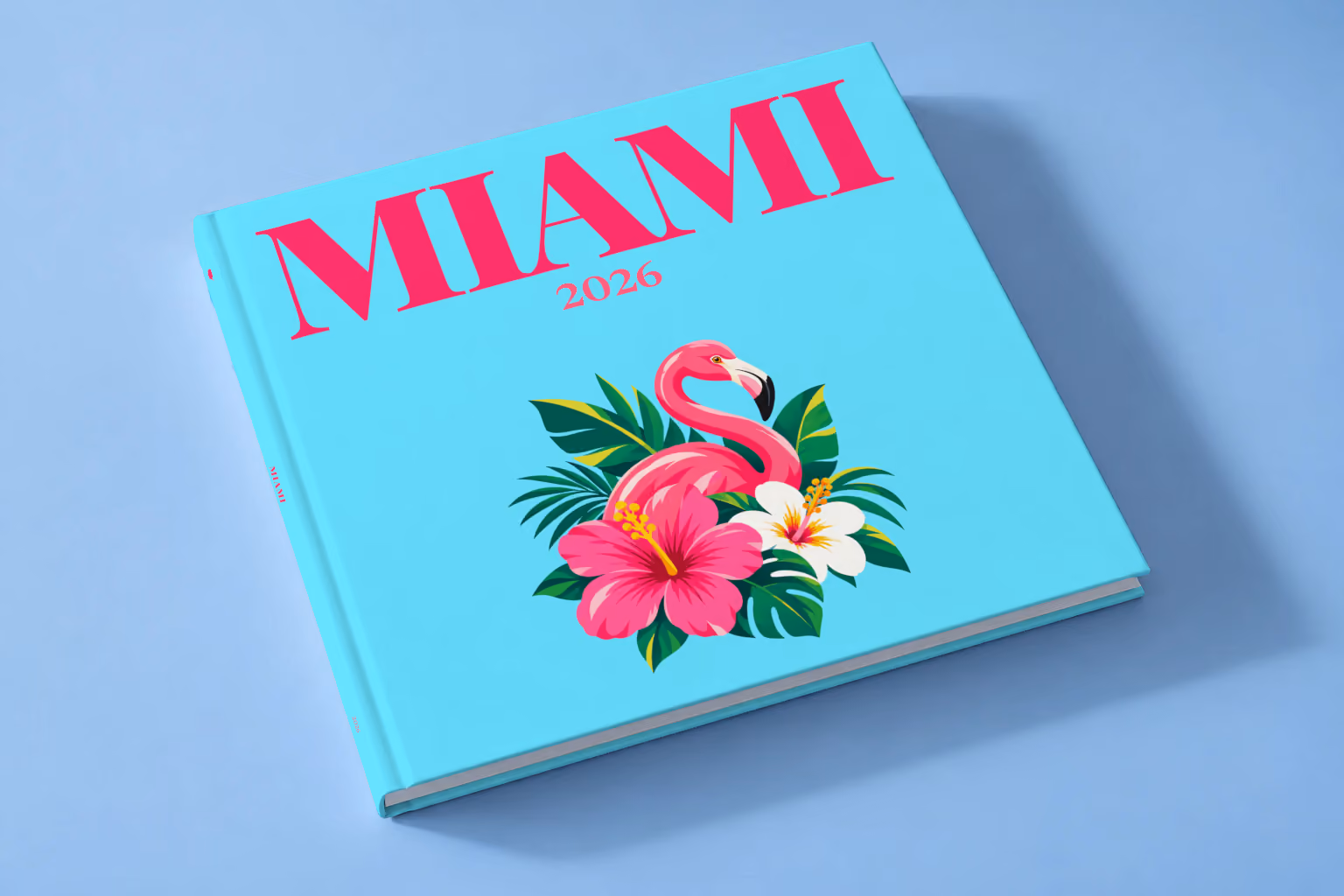 Florida square hardcover photo book with the Miami illustrated cover of a pink flamingo with hibiscus flowers and palm leaves on aqua, lying on a pale blue studio backdrop