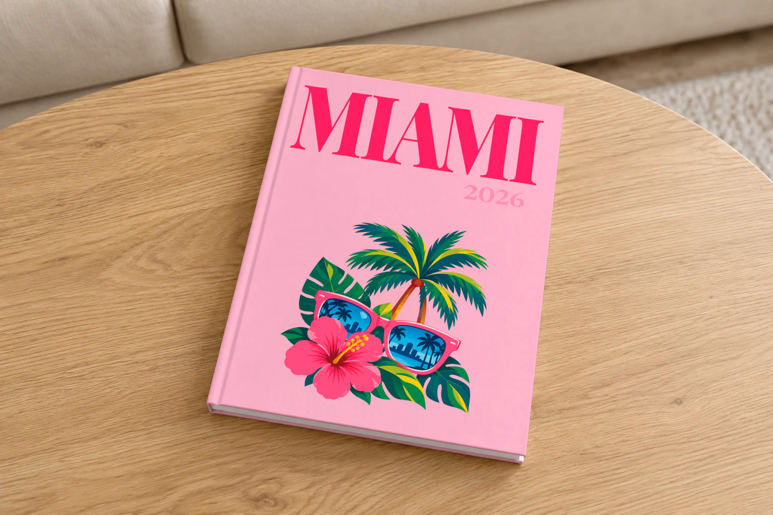 Florida hardcover photo book with the Miami illustrated cover of pink sunglasses reflecting palm trees, with hibiscus, on pink, on a round oak coffee table in a bright living room