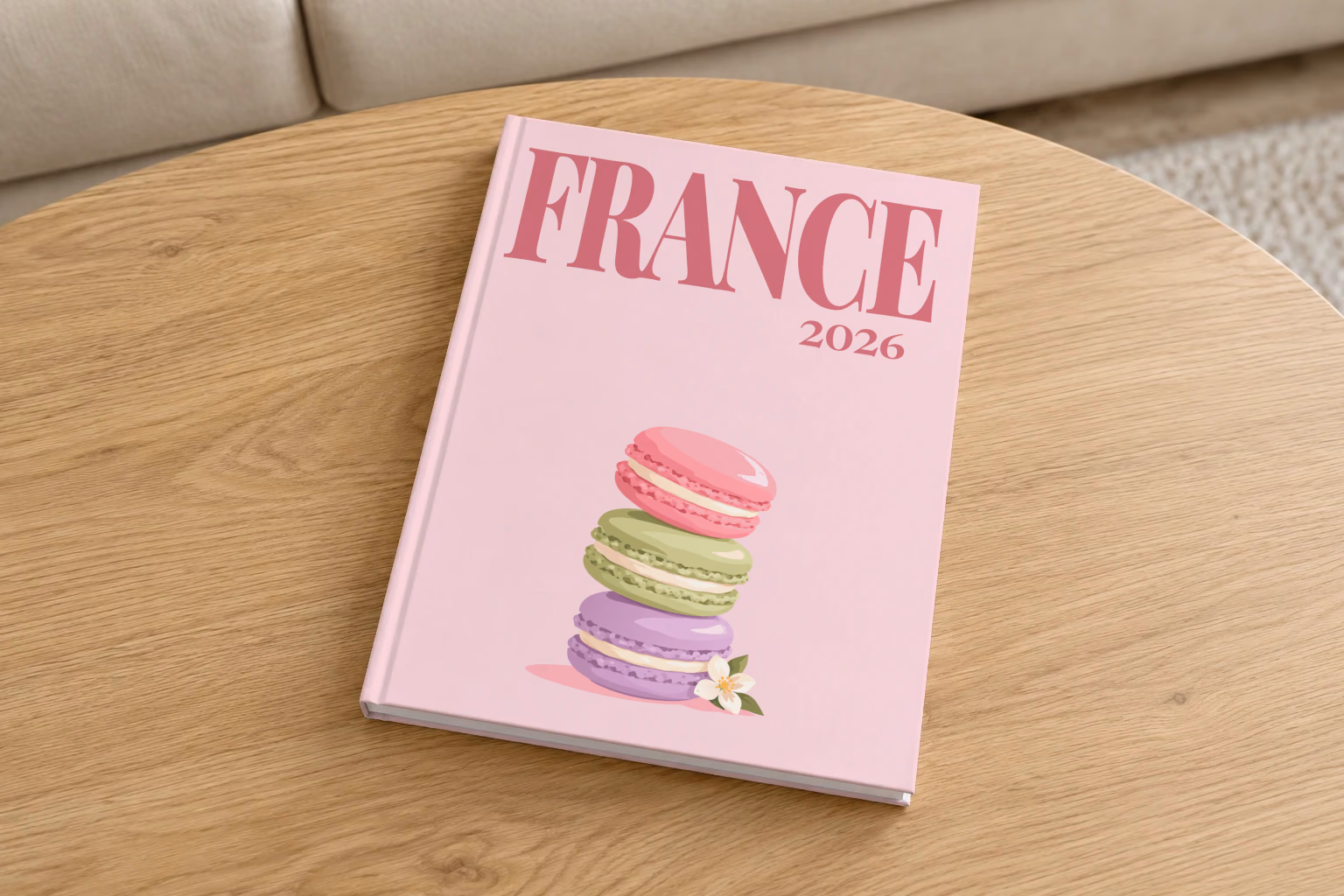 France hardcover photo book with the illustrated cover of a stack of macarons on pale pink, on a round oak coffee table in a bright living room