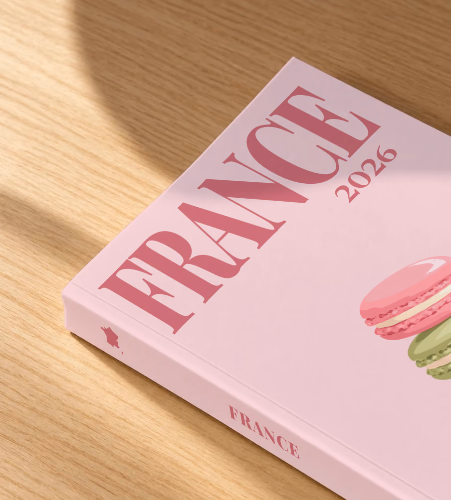 France softcover photo book with the illustrated cover of a stack of macarons on pale pink, lying on an oak desk in dappled afternoon sunlight