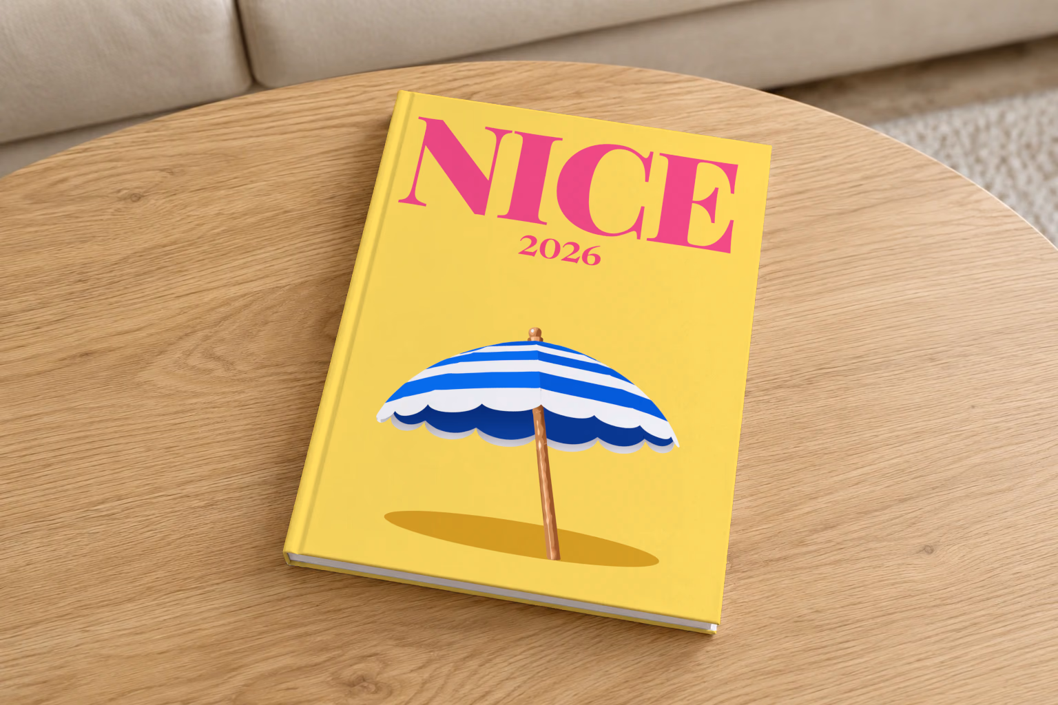 France hardcover photo book with the Nice illustrated cover of a blue and white striped beach umbrella on yellow, on a round oak coffee table in a bright living room