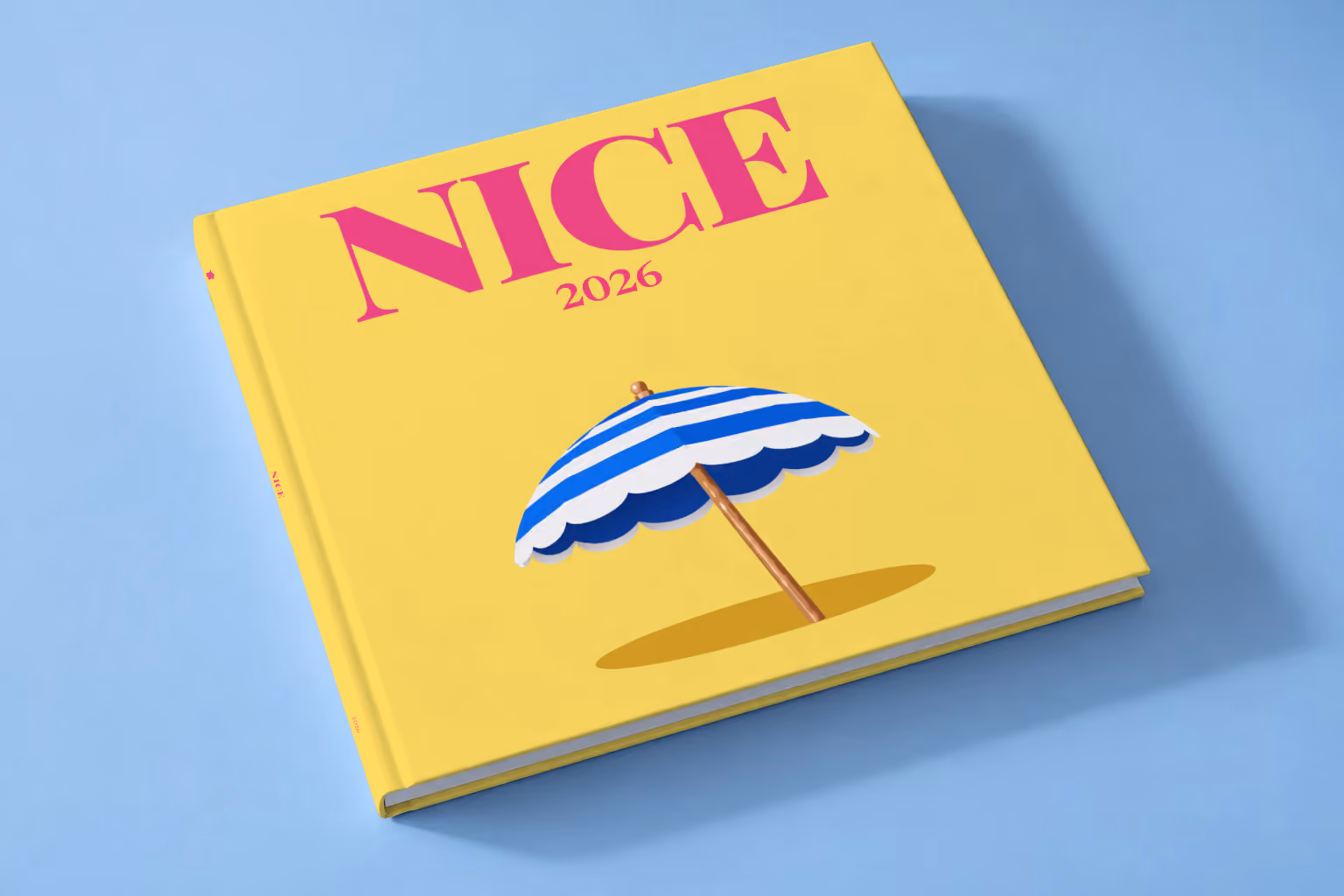 France square hardcover photo book with the Nice illustrated cover of a blue and white striped beach umbrella on yellow, lying on a pale blue studio backdrop