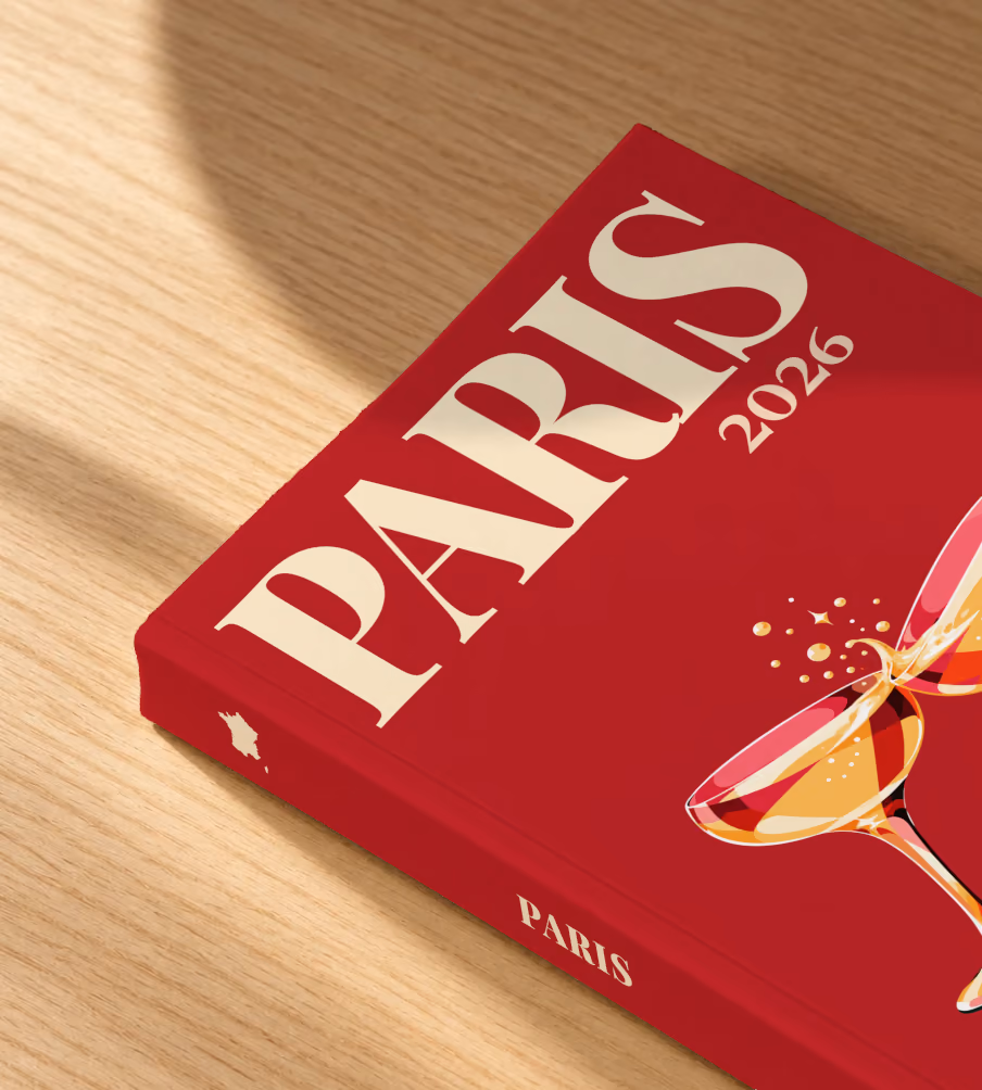 France softcover photo book with the Paris illustrated cover of two champagne coupes on deep red, lying on an oak desk in dappled afternoon sunlight
