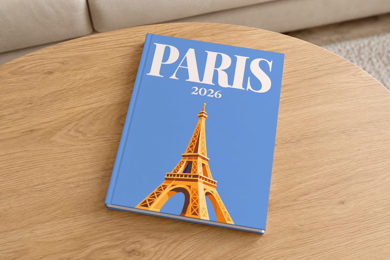 France hardcover photo book with the Paris illustrated cover of a gold Eiffel Tower on blue, on a round oak coffee table in a bright living room