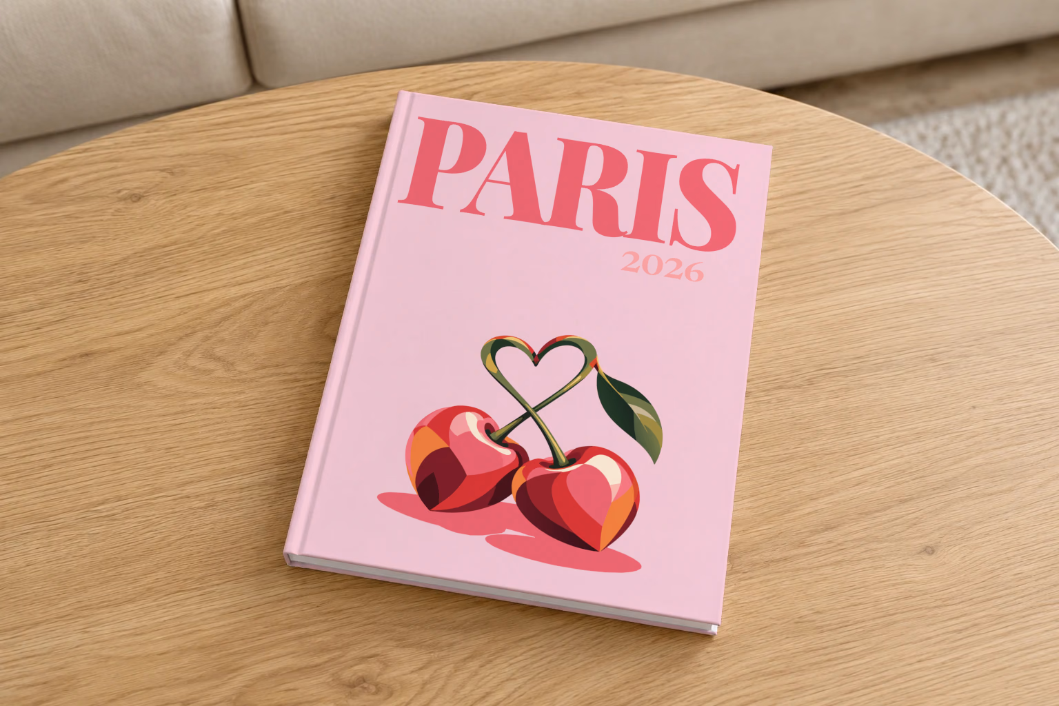 France hardcover photo book with the Paris illustrated cover of cherries with heart-shaped stems on pale pink, on a round oak coffee table in a bright living room