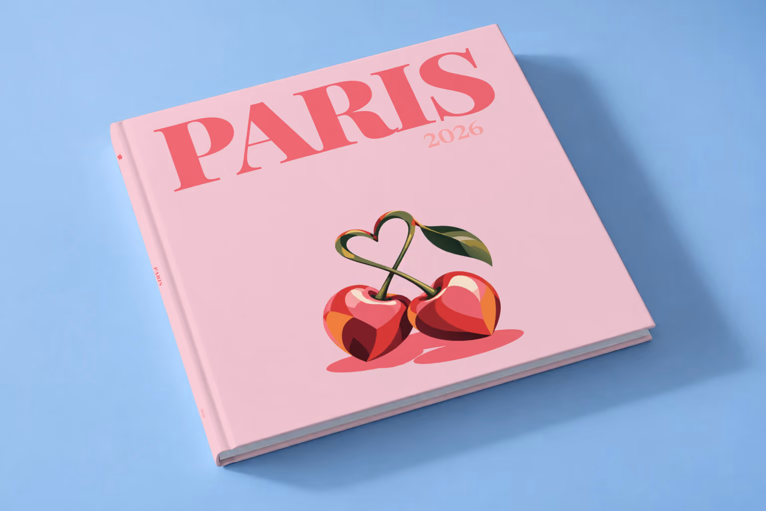 France square hardcover photo book with the Paris illustrated cover of cherries with heart-shaped stems on pale pink, lying on a pale blue studio backdrop