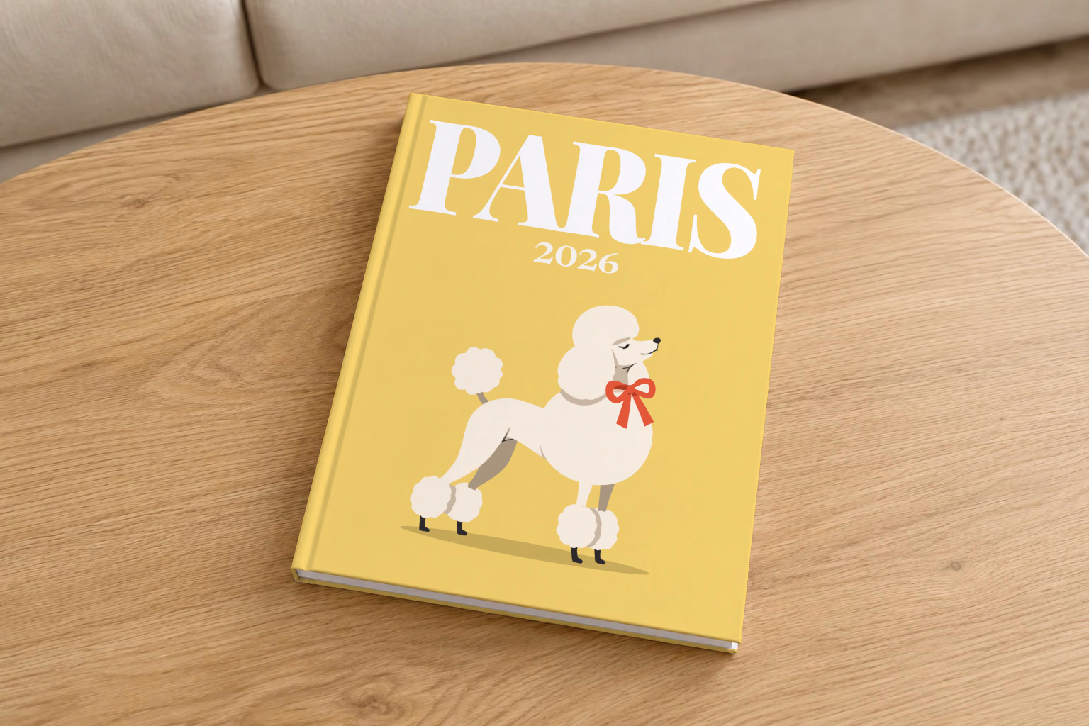France hardcover photo book with the Paris illustrated cover of a white poodle with a red bow on yellow, on a round oak coffee table in a bright living room