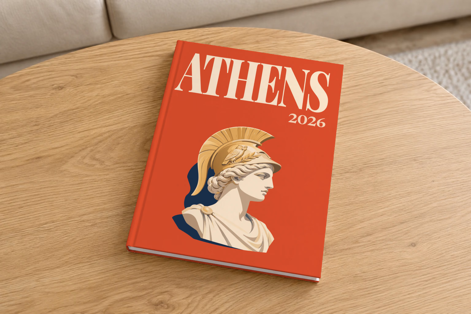 Greece hardcover photo book with the Athens illustrated cover of a bust of Athena in a helmet on red, on a round oak coffee table in a bright living room
