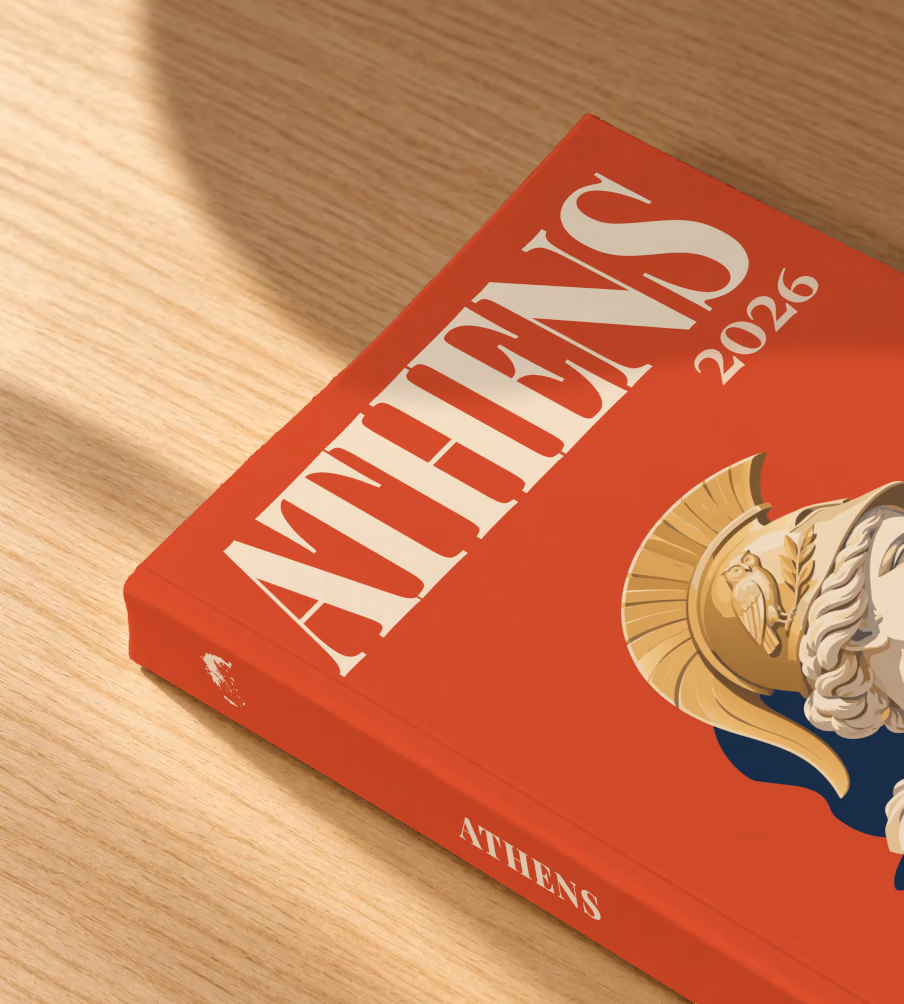 Greece softcover photo book with the Athens illustrated cover of a bust of Athena in a helmet on red, lying on an oak desk in dappled afternoon sunlight
