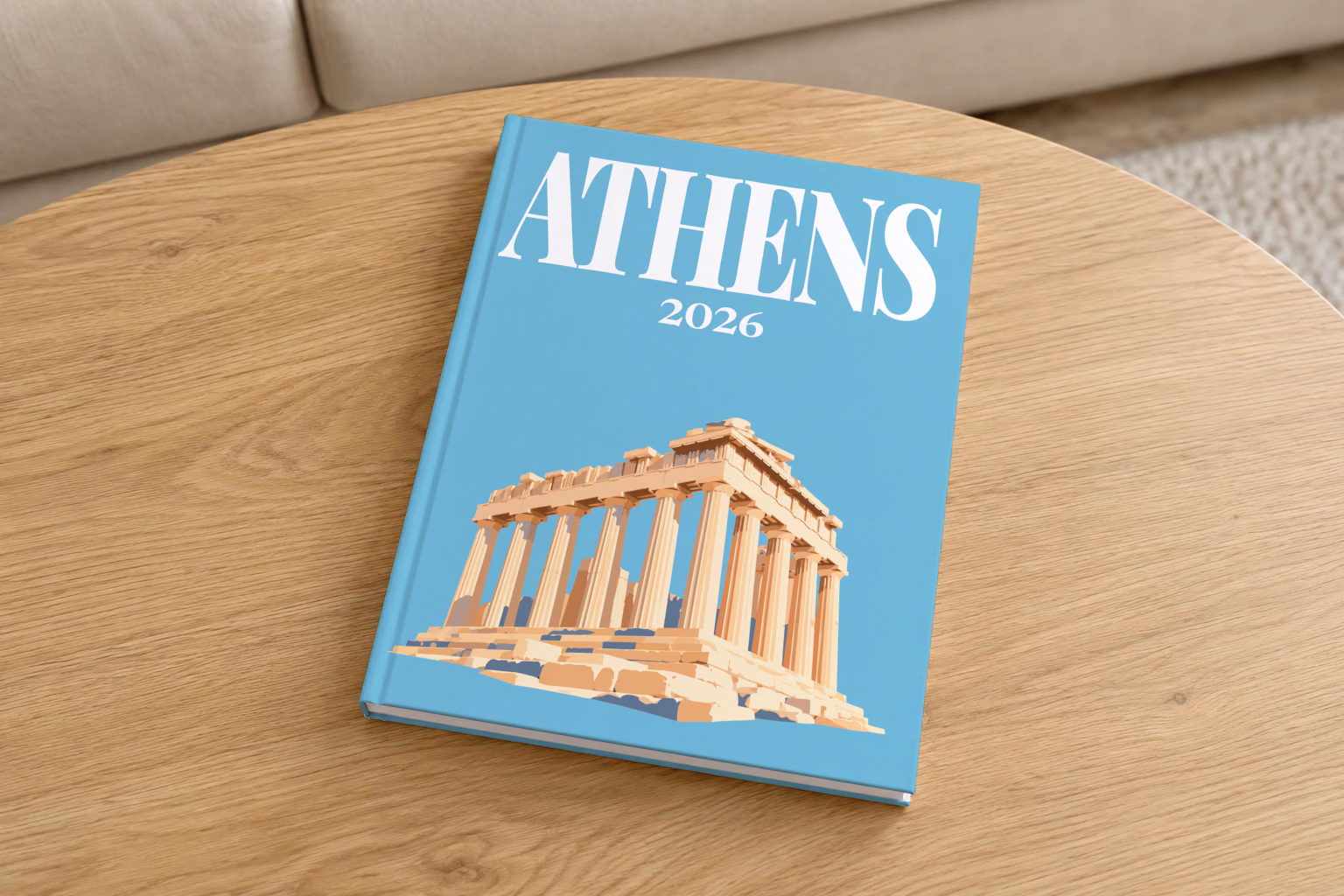 Greece hardcover photo book with the Athens illustrated cover of the Parthenon on blue, on a round oak coffee table in a bright living room