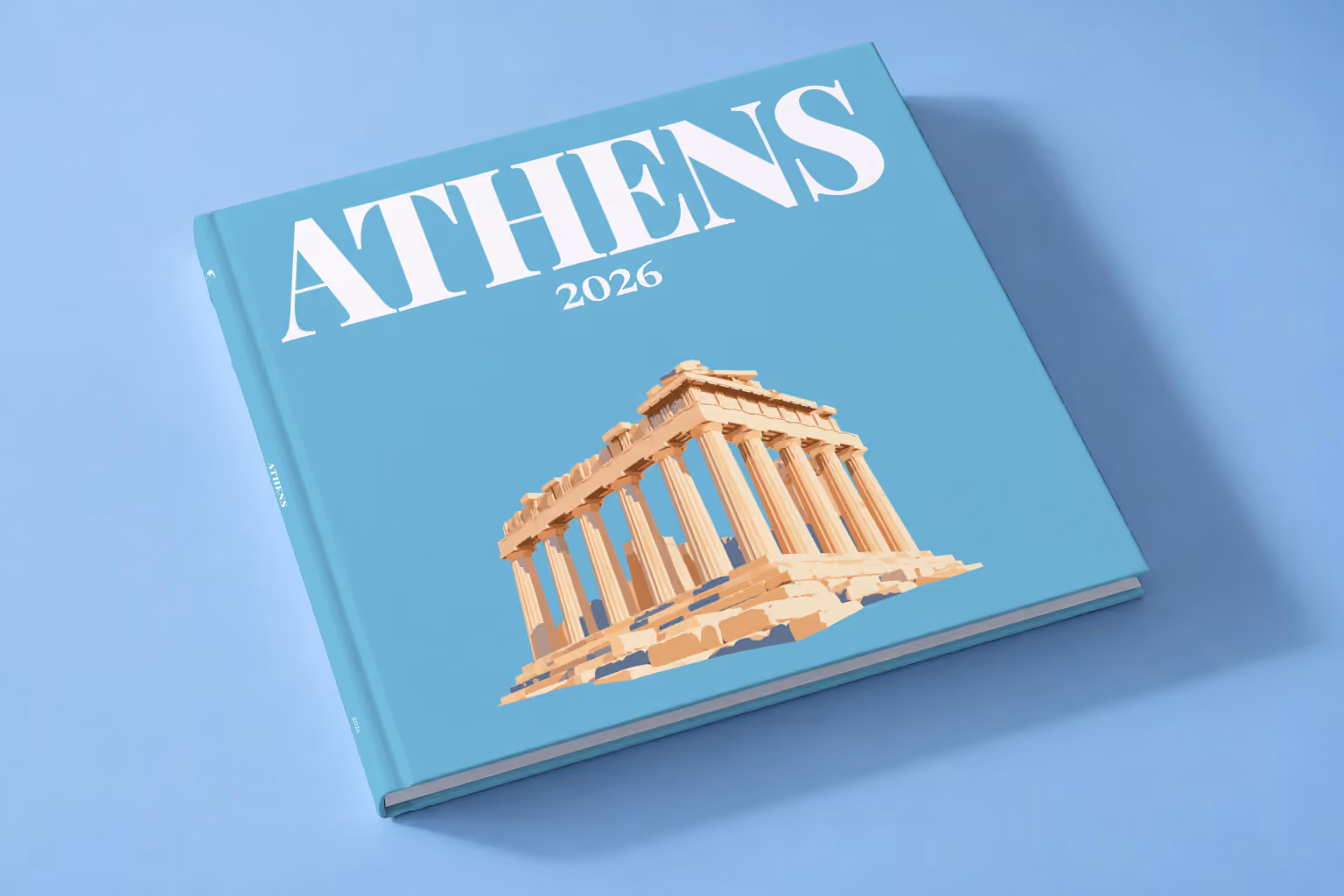 Greece square hardcover photo book with the Athens illustrated cover of the Parthenon on blue, lying on a pale blue studio backdrop