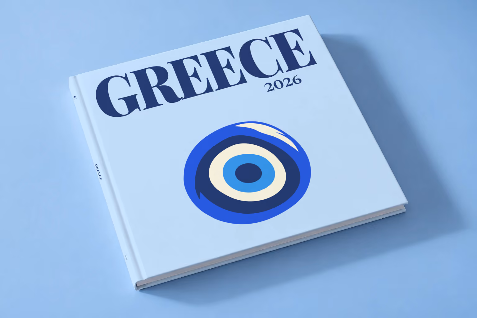 Greece square hardcover photo book with the illustrated cover of an evil eye on pale blue, lying on a pale blue studio backdrop