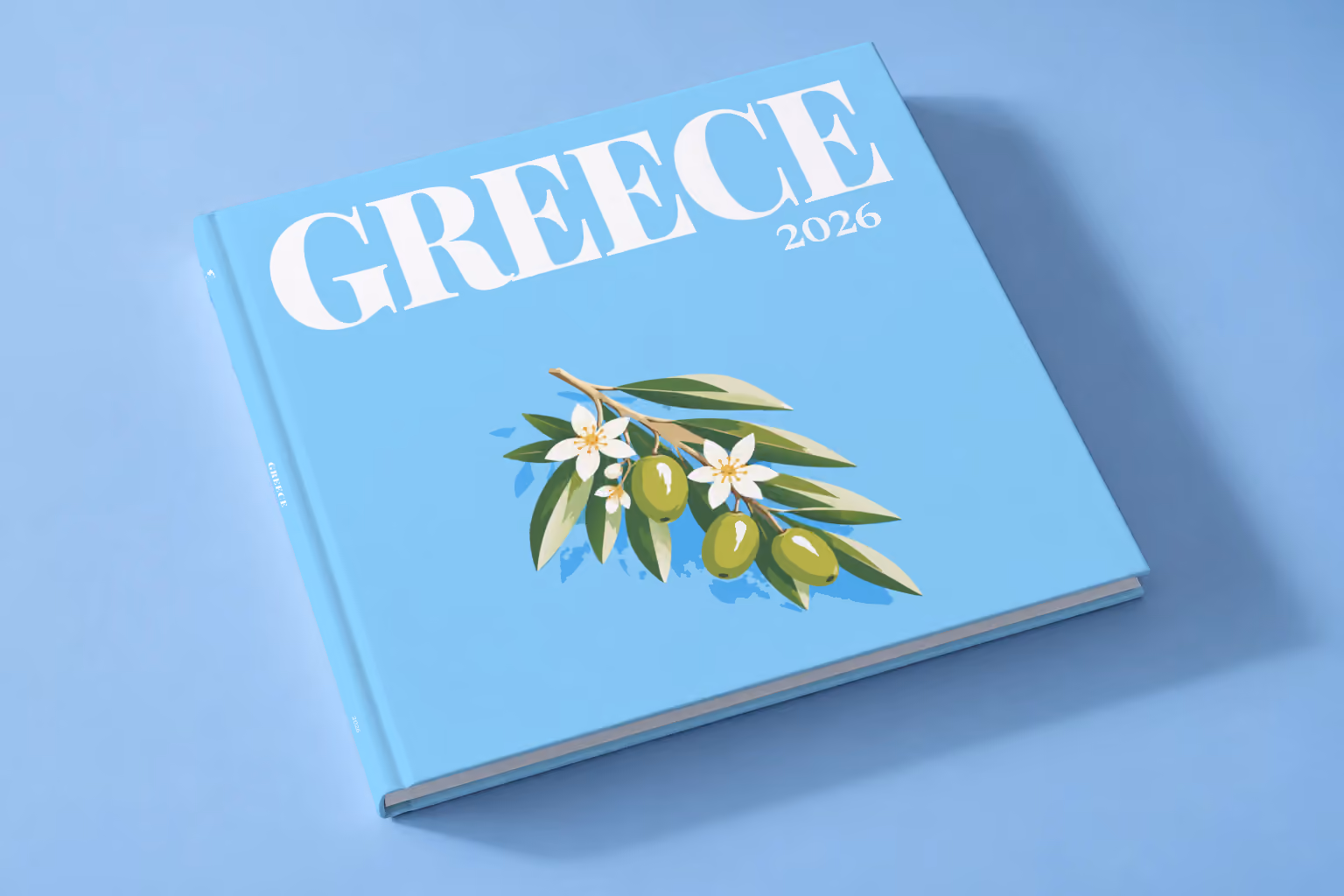 Greece square hardcover photo book with the illustrated cover of an olive branch with blossom on sky blue, lying on a pale blue studio backdrop