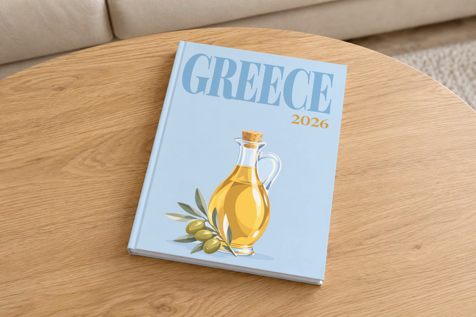 Greece hardcover photo book with the illustrated cover of a bottle of olive oil and olives on pale blue, on a round oak coffee table in a bright living room