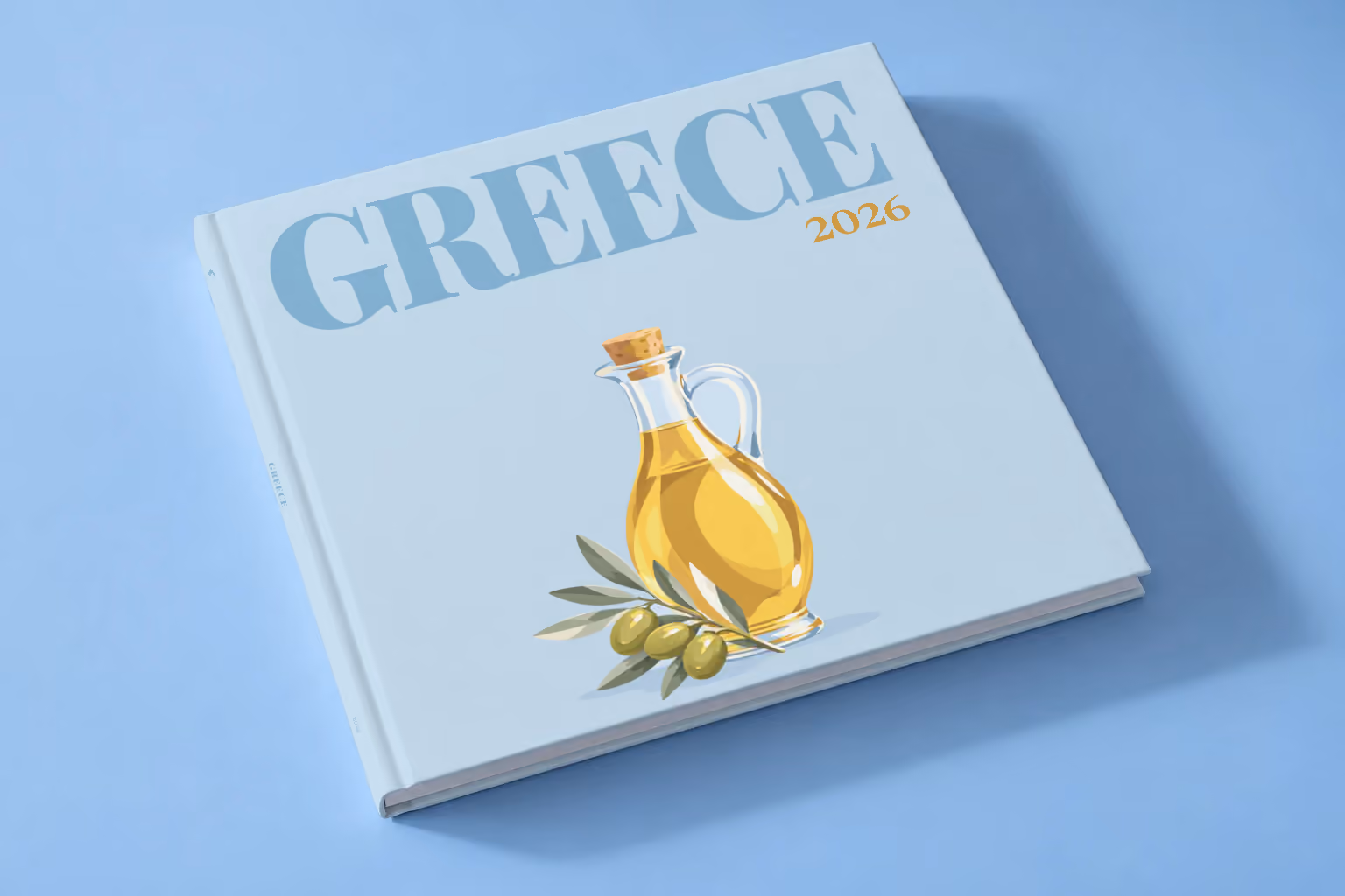 Greece square hardcover photo book with the illustrated cover of a bottle of olive oil and olives on pale blue, lying on a pale blue studio backdrop