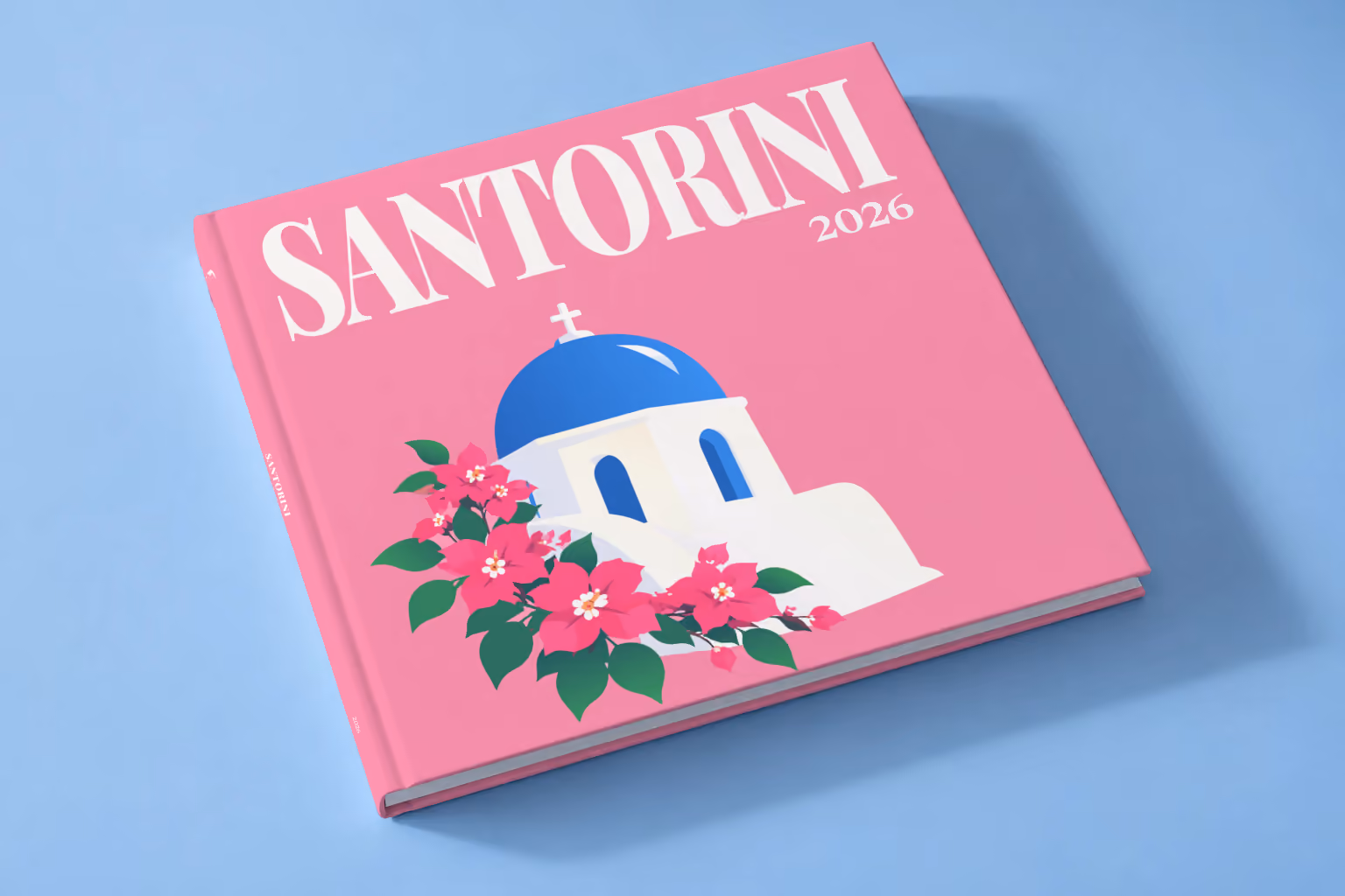 Greece square hardcover photo book with the Santorini illustrated cover of a blue-domed chapel and bougainvillea on pink, lying on a pale blue studio backdrop