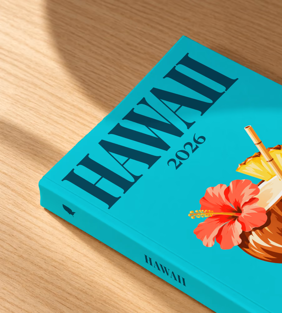 Hawaii softcover photo book with the illustrated cover of a coconut drink with hibiscus and pineapple on turquoise, lying on an oak desk in dappled afternoon sunlight