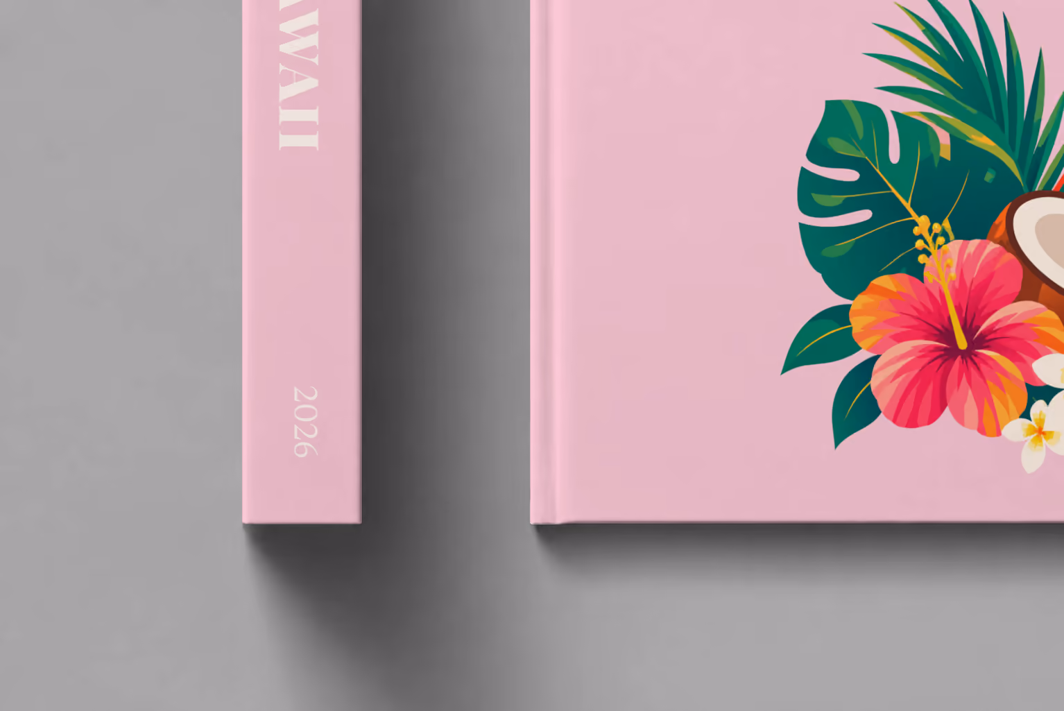 Hawaii hardcover photo book with the illustrated cover of a tropical bouquet with hibiscus, a coconut and palm leaves on pale pink, shown close up beside its spine on a pale grey studio surface