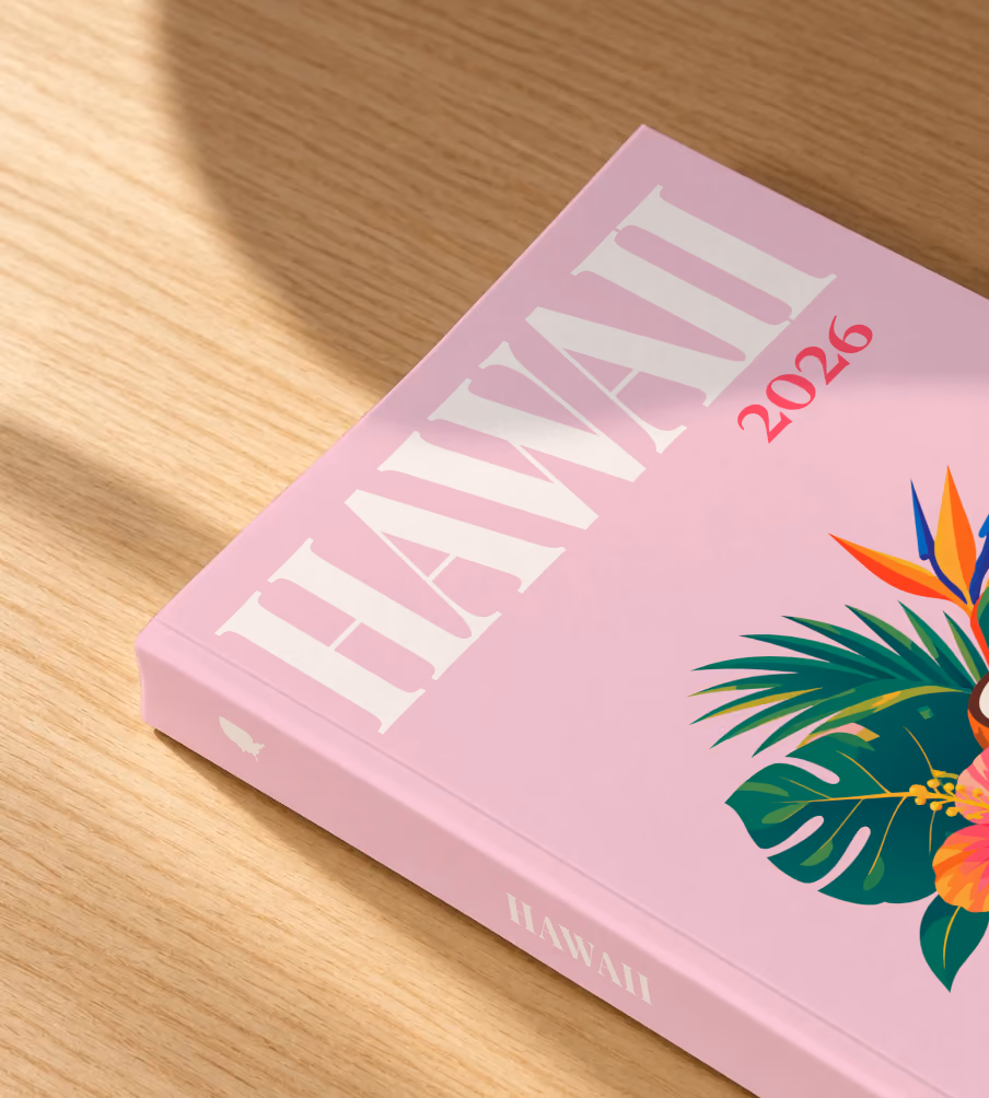 Hawaii softcover photo book with the illustrated cover of a tropical bouquet with hibiscus, a coconut and palm leaves on pale pink, lying on an oak desk in dappled afternoon sunlight