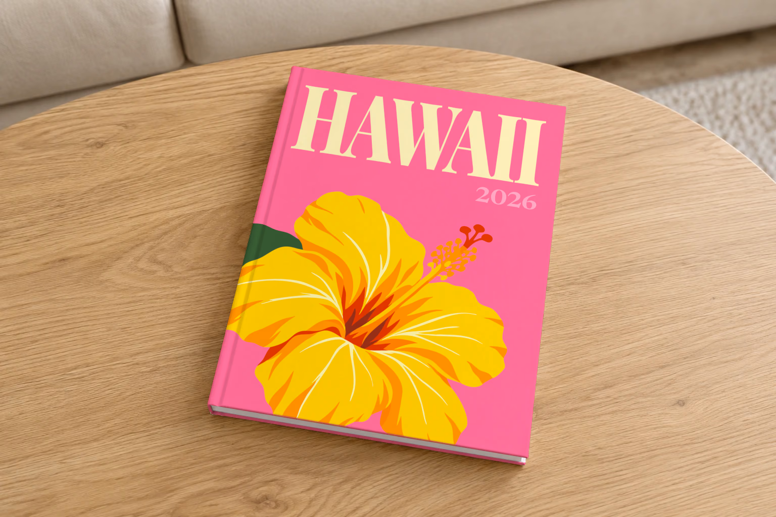 Hawaii hardcover photo book with the illustrated cover of a yellow hibiscus on pink, on a round oak coffee table in a bright living room