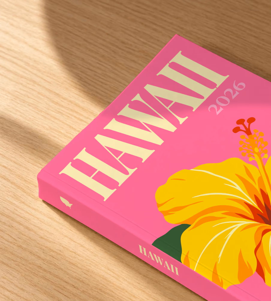 Hawaii softcover photo book with the illustrated cover of a yellow hibiscus on pink, lying on an oak desk in dappled afternoon sunlight