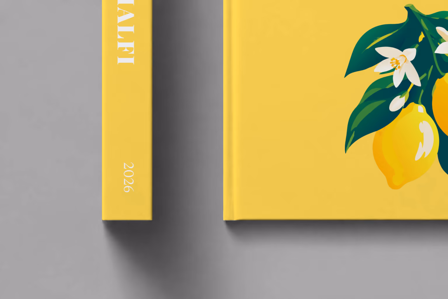 Italy hardcover photo book with the Amalfi illustrated cover of lemons and blossom on yellow, shown close up beside its spine on a pale grey studio surface
