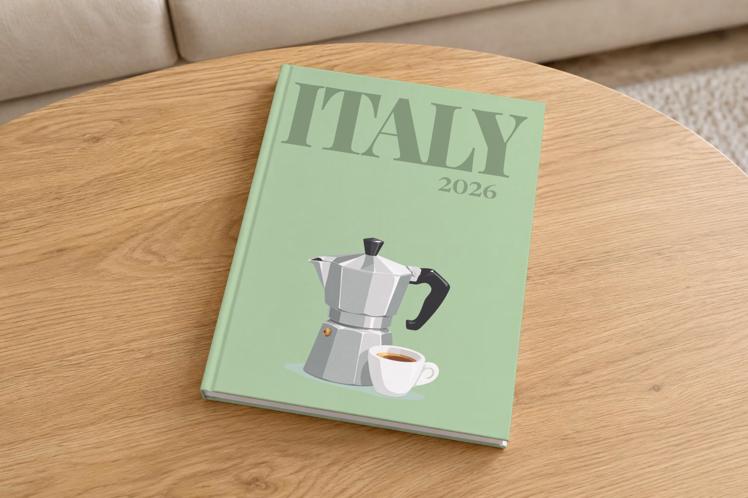 Italy hardcover photo book with the illustrated cover of a moka pot and an espresso cup on sage green, on a round oak coffee table in a bright living room