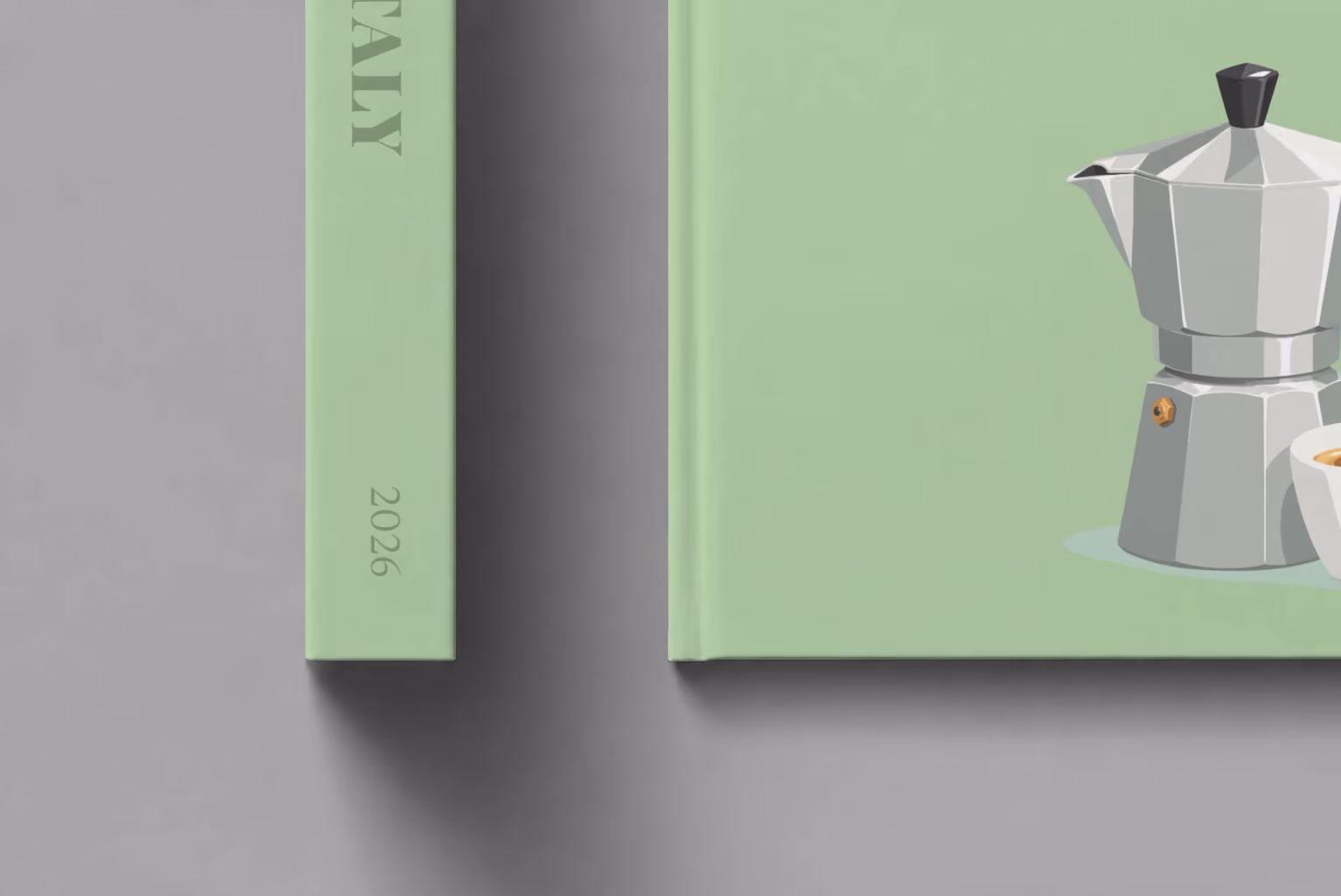 Italy hardcover photo book with the illustrated cover of a moka pot and an espresso cup on sage green, shown close up beside its spine on a pale grey studio surface