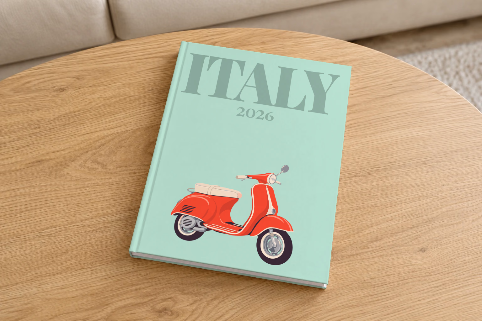 Italy hardcover photo book with the illustrated cover of a red Vespa scooter on mint green, on a round oak coffee table in a bright living room