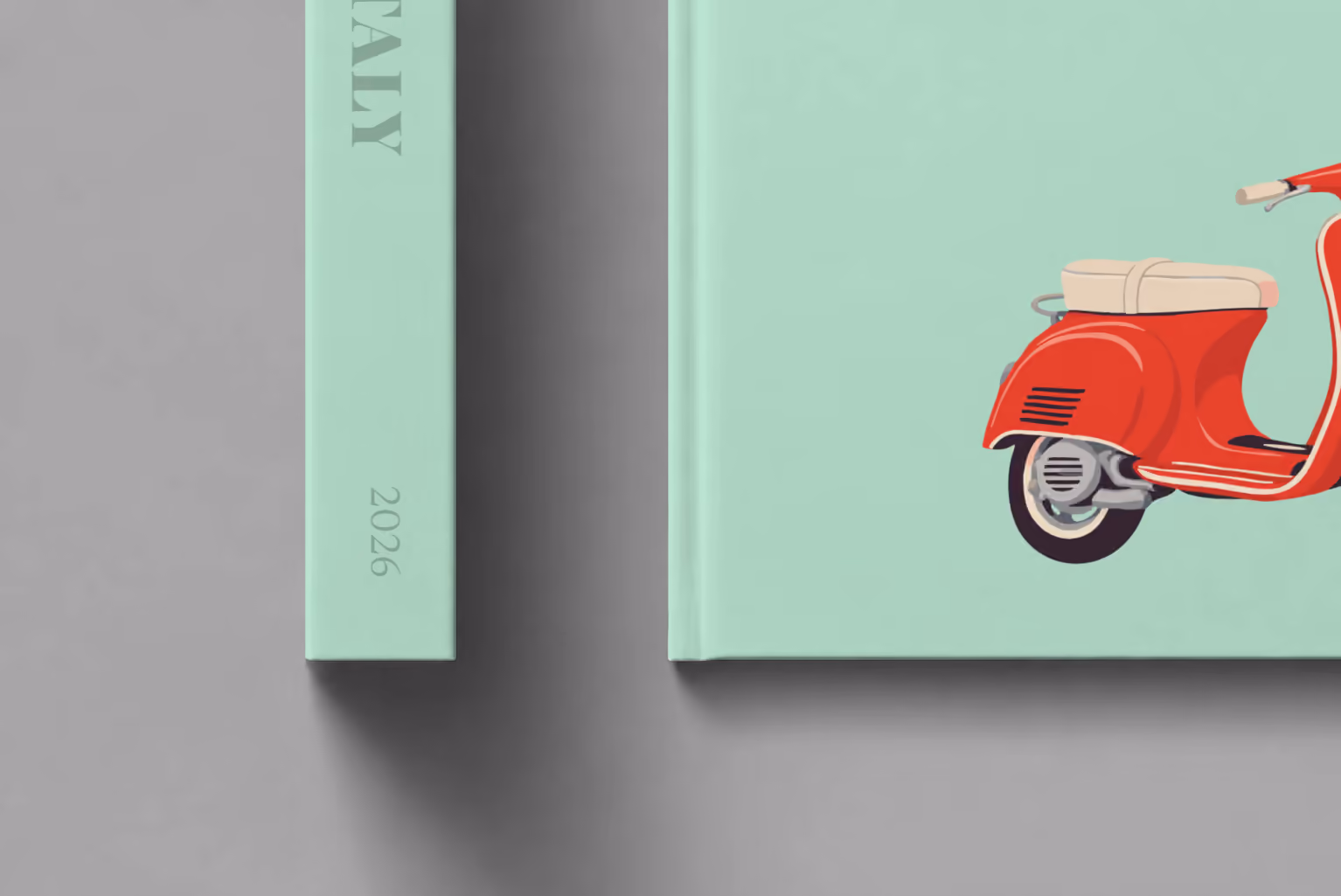 Italy hardcover photo book with the illustrated cover of a red Vespa scooter on mint green, shown close up beside its spine on a pale grey studio surface