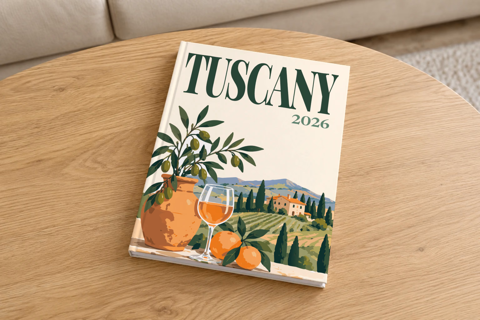 Italy hardcover photo book with the Tuscany illustrated cover of an olive tree, a glass of wine and Tuscan vineyards on cream, on a round oak coffee table in a bright living room
