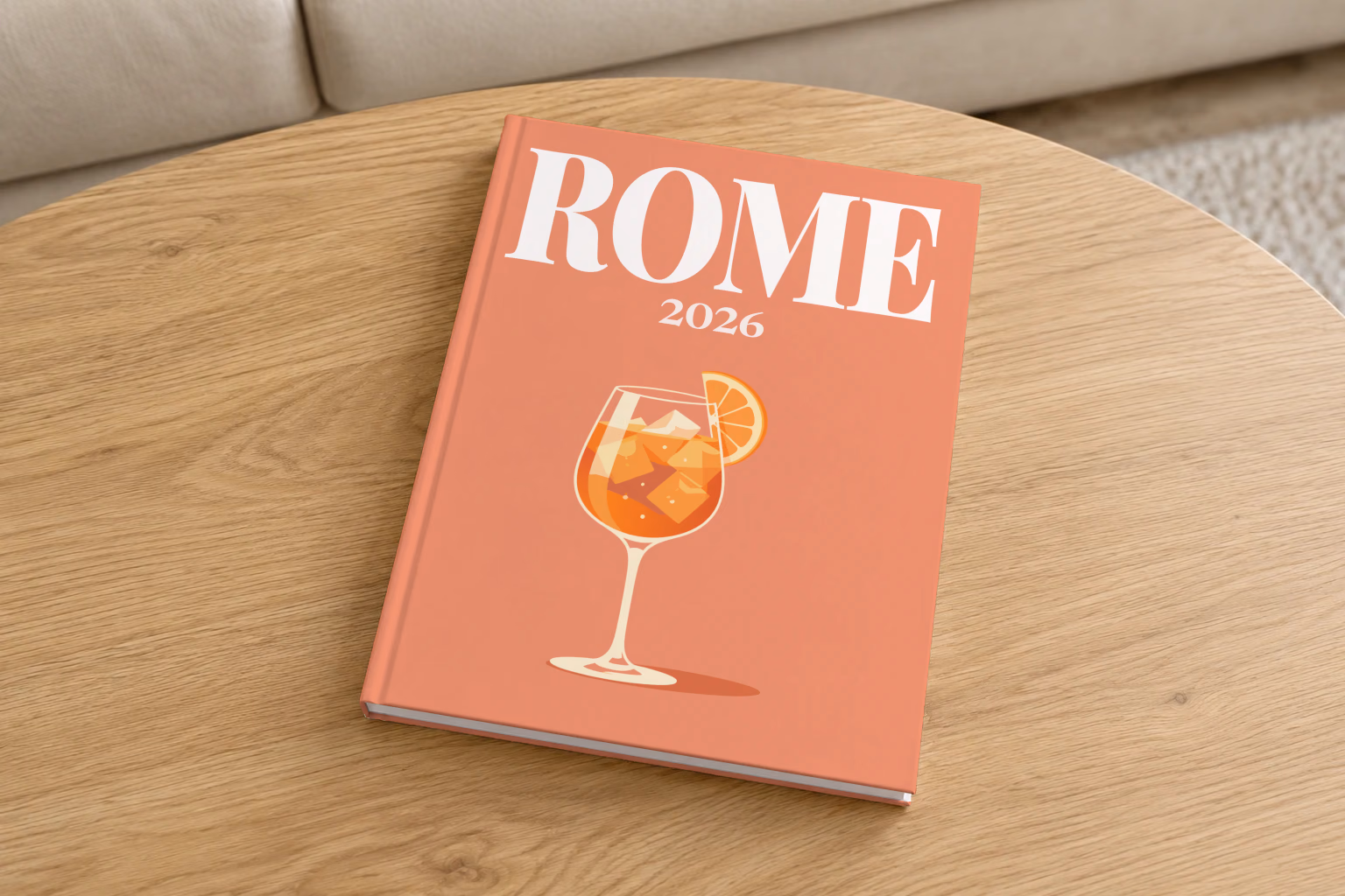 Italy hardcover photo book with the Rome illustrated cover of an Aperol spritz on coral, on a round oak coffee table in a bright living room