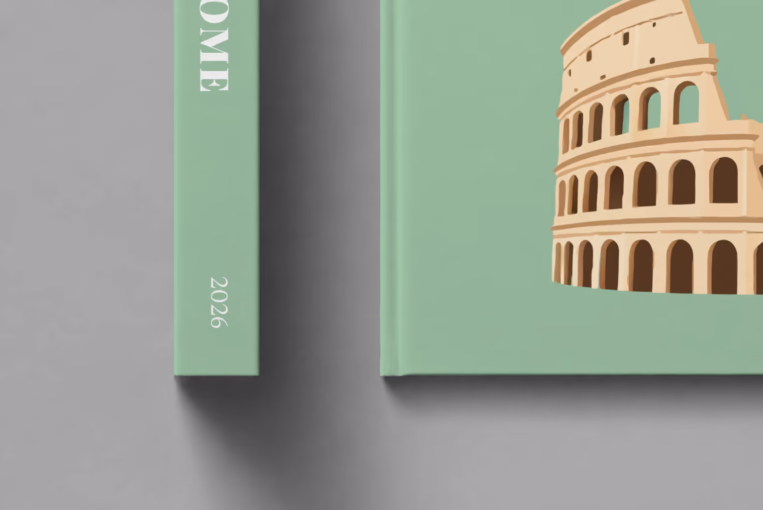 Italy hardcover photo book with the Rome illustrated cover of the Colosseum and cypress trees on sage green, shown close up beside its spine on a pale grey studio surface