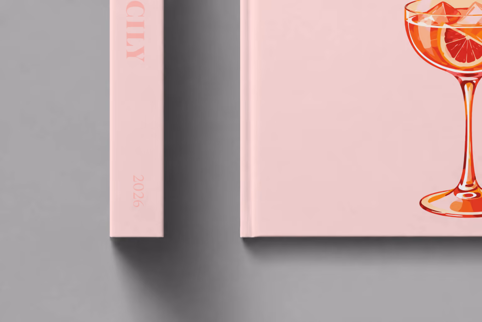 Italy hardcover photo book with the Sicily illustrated cover of a blood orange spritz on pale pink, shown close up beside its spine on a pale grey studio surface