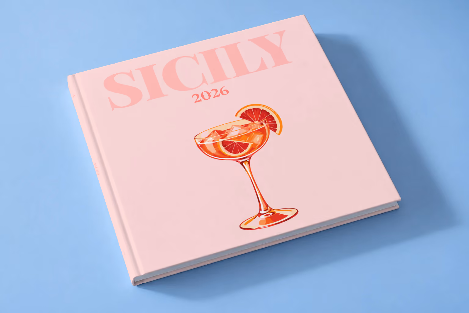 Italy square hardcover photo book with the Sicily illustrated cover of a blood orange spritz on pale pink, lying on a pale blue studio backdrop