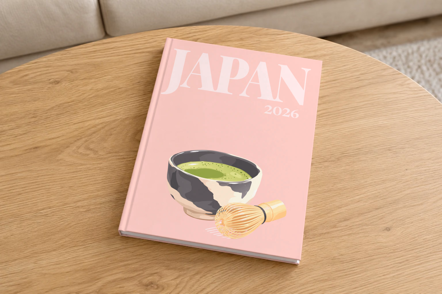 Japan hardcover photo book with the illustrated cover of a bowl of matcha and a whisk on pale pink, on a round oak coffee table in a bright living room