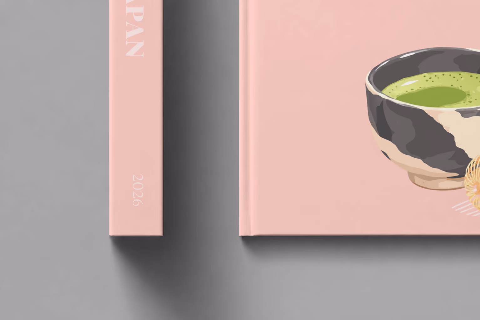 Japan hardcover photo book with the illustrated cover of a bowl of matcha and a whisk on pale pink, shown close up beside its spine on a pale grey studio surface