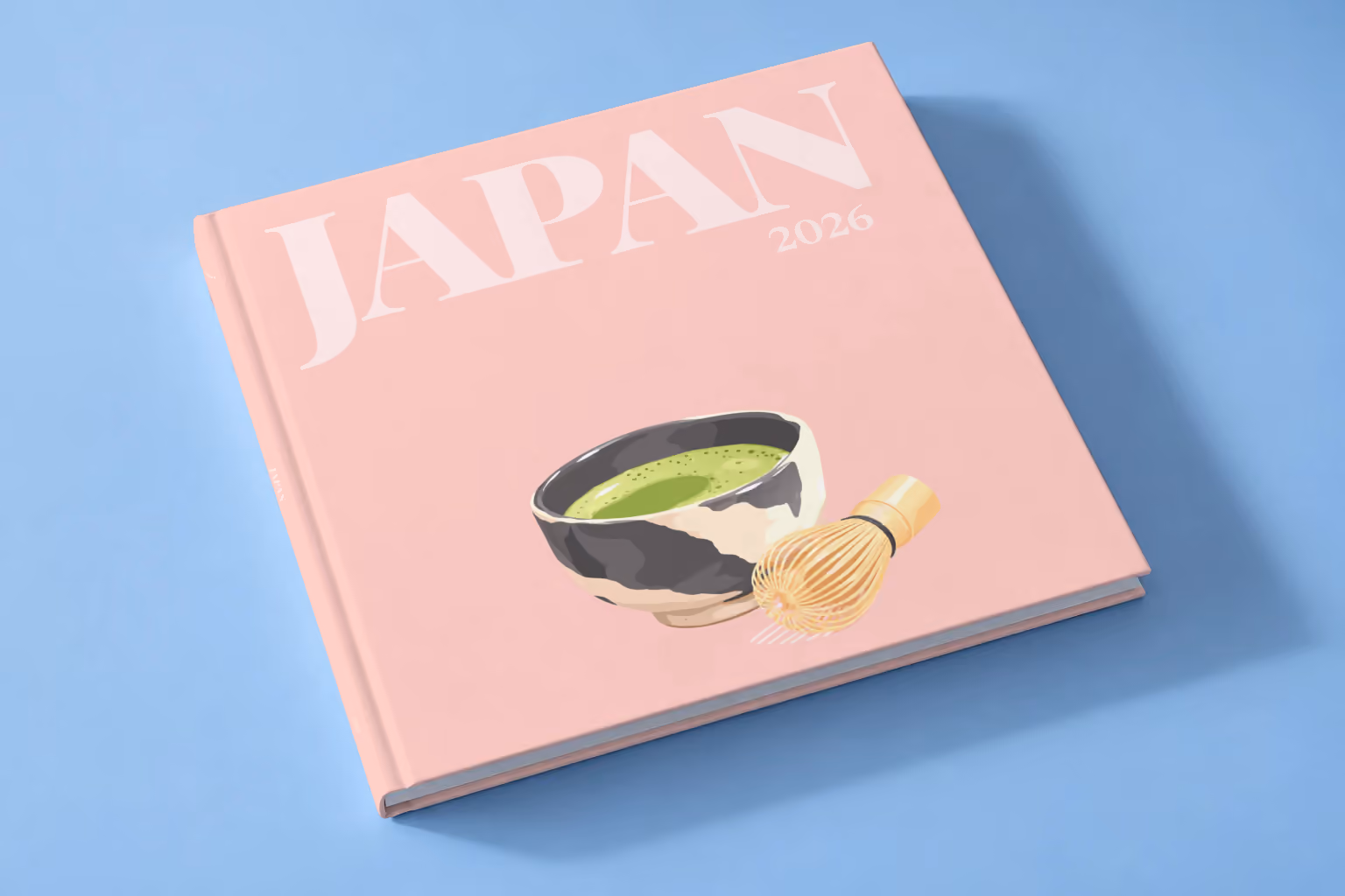 Japan square hardcover photo book with the illustrated cover of a bowl of matcha and a whisk on pale pink, lying on a pale blue studio backdrop