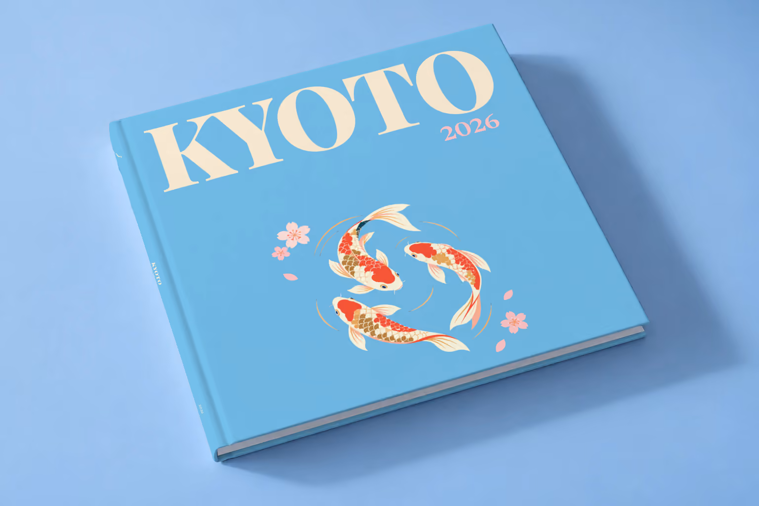 Japan square hardcover photo book with the Kyoto illustrated cover of koi and cherry blossom on sky blue, lying on a pale blue studio backdrop