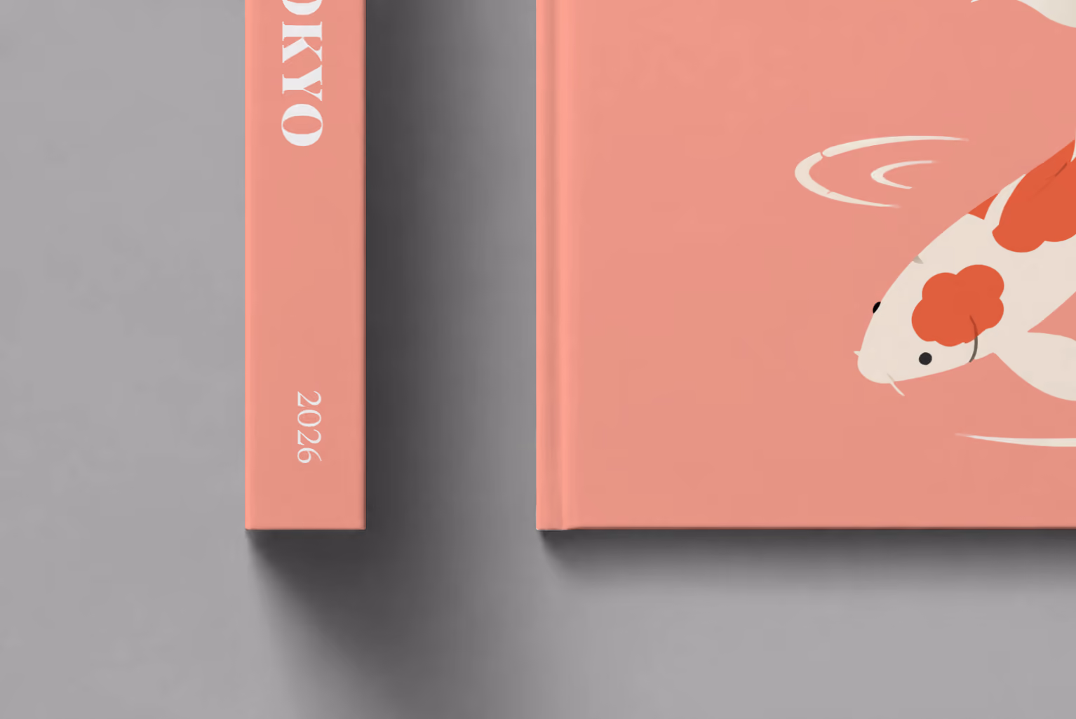Japan hardcover photo book with the Tokyo illustrated cover of a koi on coral pink, shown close up beside its spine on a pale grey studio surface