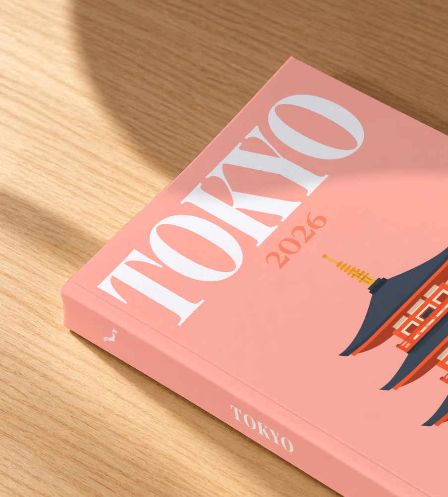 Japan softcover photo book with the Tokyo illustrated cover of a pagoda on salmon pink, lying on an oak desk in dappled afternoon sunlight