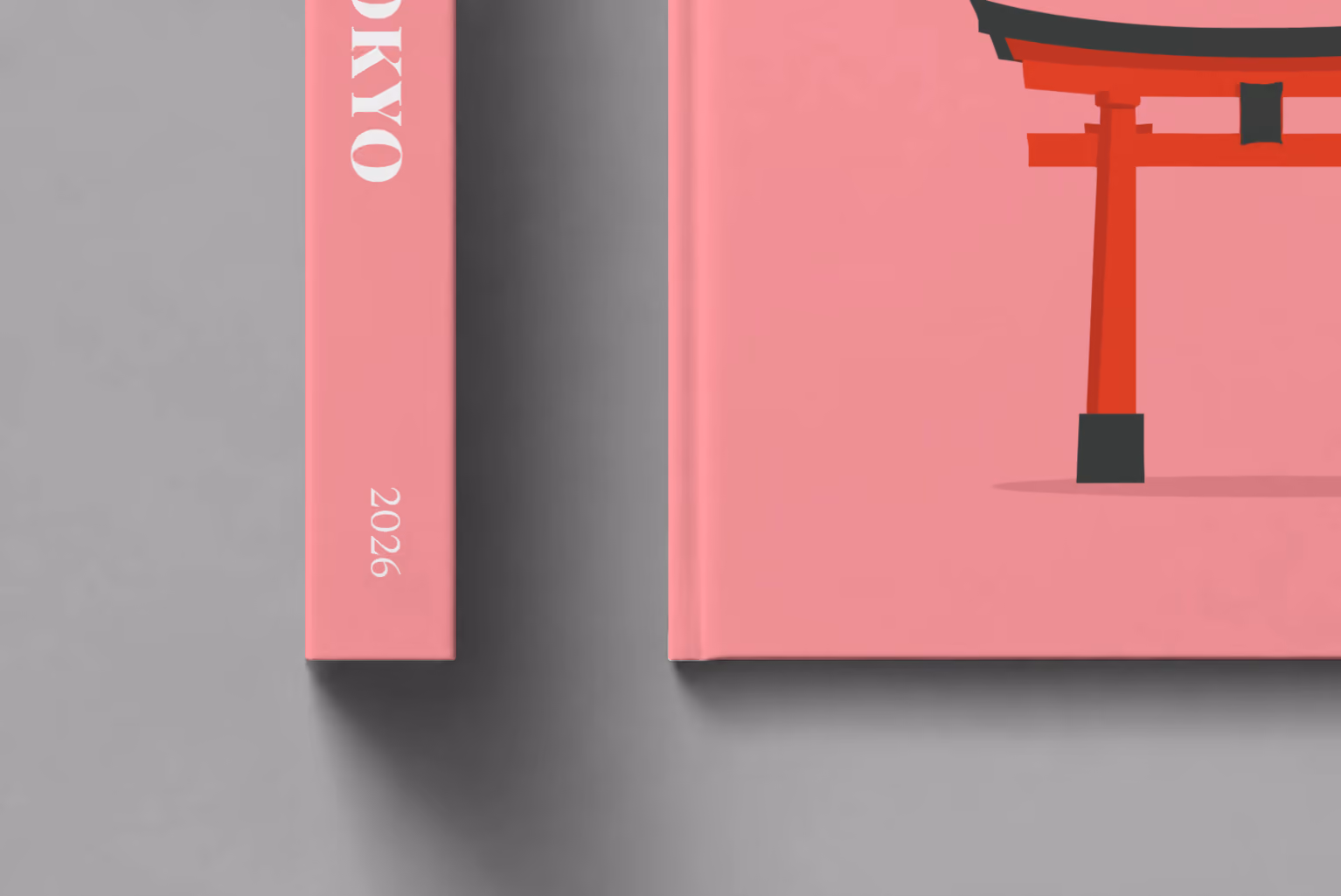 Japan hardcover photo book with the Tokyo illustrated cover of a red torii gate and petals on pink, shown close up beside its spine on a pale grey studio surface