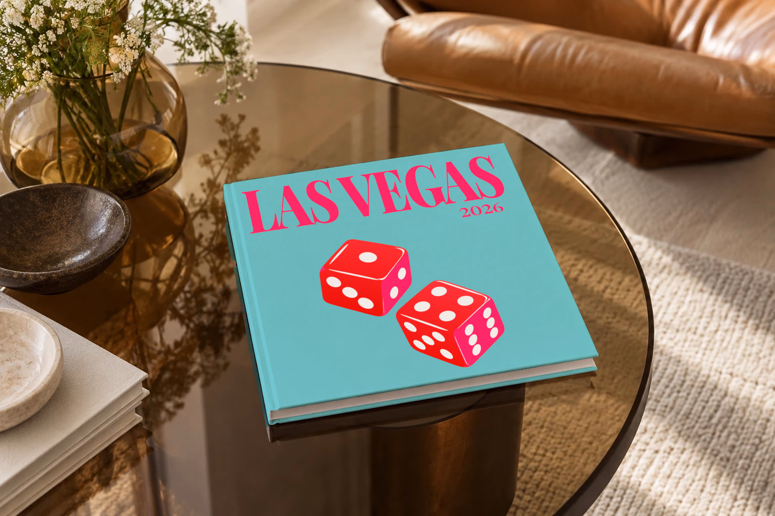 Las Vegas square hardcover photo book with the illustrated cover of a pair of red casino dice on turquoise, on a smoked glass coffee table beside a leather armchair in warm afternoon light