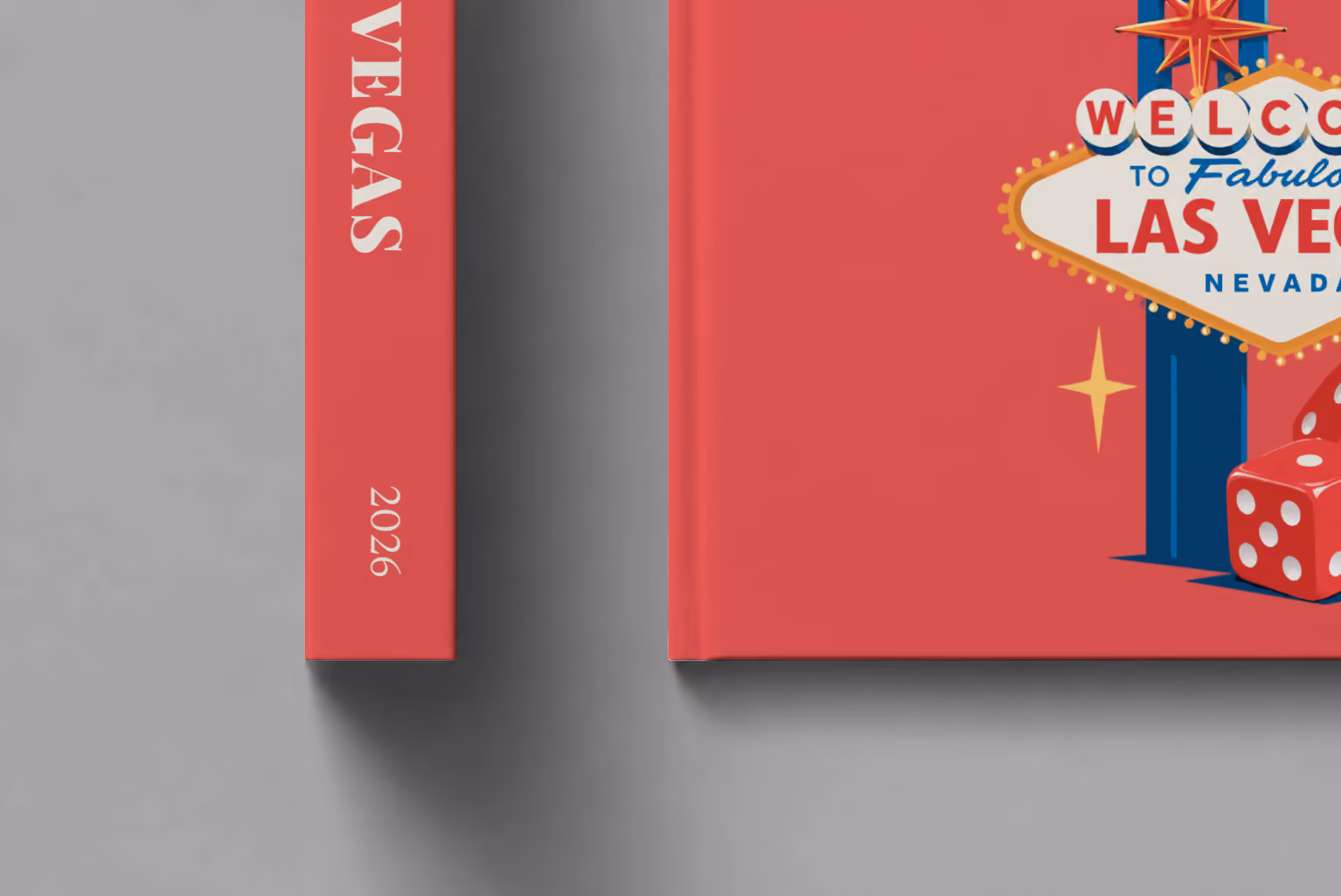 Las Vegas hardcover photo book with the illustrated cover of the Welcome to Fabulous Las Vegas sign and red dice on red, shown close up beside its spine on a pale grey studio surface