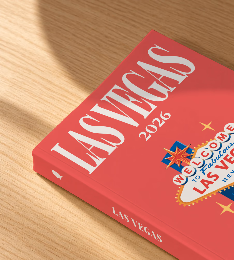 Las Vegas softcover photo book with the illustrated cover of the Welcome to Fabulous Las Vegas sign and red dice on red, lying on an oak desk in dappled afternoon sunlight